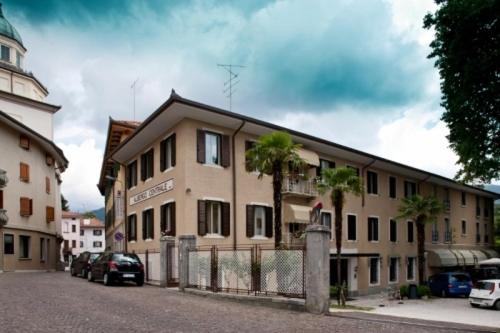 a large building with palm trees in front of it at Albergo Centrale in Tarcento