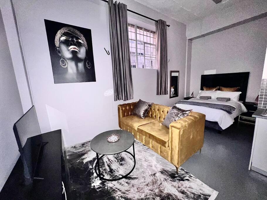 sala de estar con sofá y cama en `Luxury Cosy City Apartment, en Johannesburgo