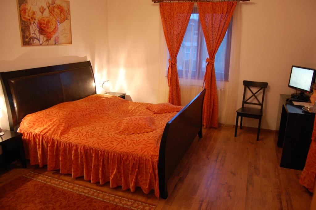 a bedroom with a bed with orange sheets and a window at Pension Bavaria in Braşov