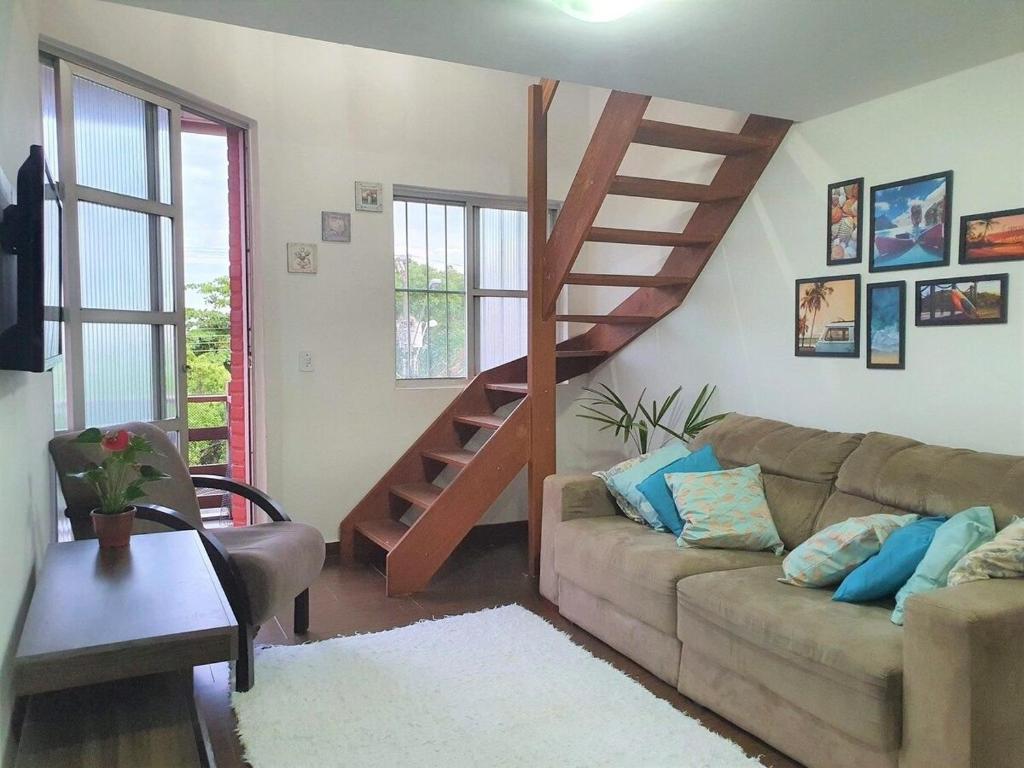 a living room with a couch and a spiral staircase at Estada inesquecível 01 Guarapari in Guarapari