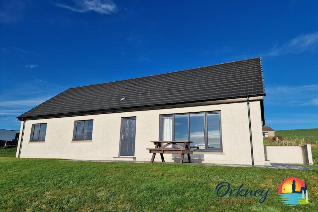 uma casa com uma mesa de piquenique em frente em Quoylee, Stromness, Orkney - OR00309F em Orkney