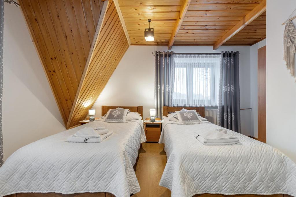 two beds in a room with wooden ceilings at Villa Kucówka in Brzegi
