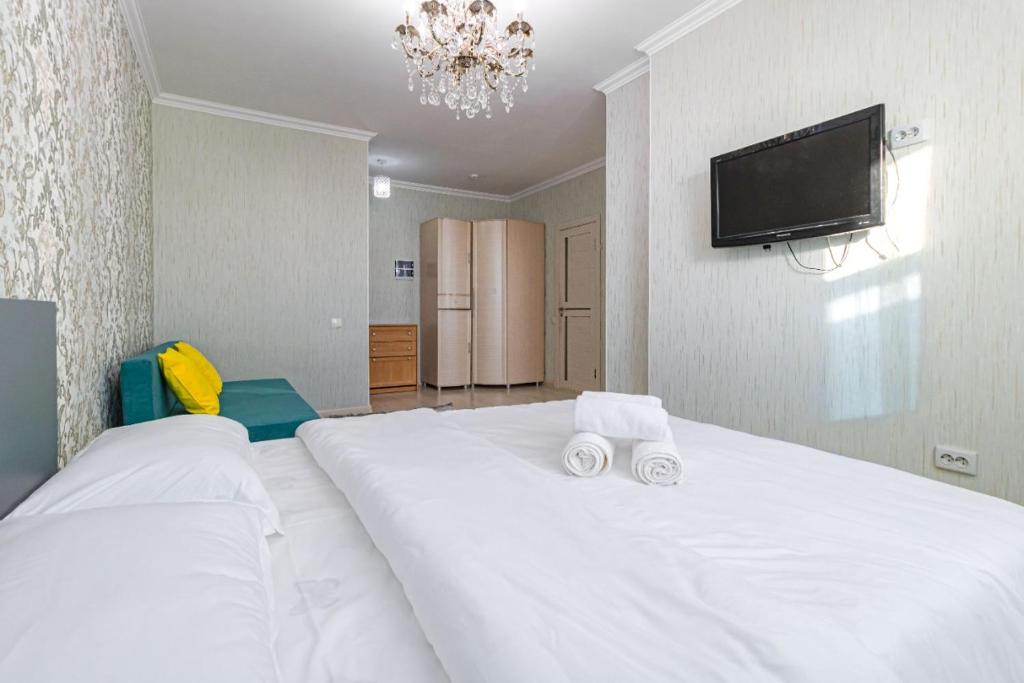 um quarto com uma grande cama branca e uma televisão de ecrã plano em ЖК 7Я em Astana