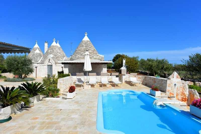 a large swimming pool in front of a house at Trullo Antico with exclusive swimming pool in Cisternino
