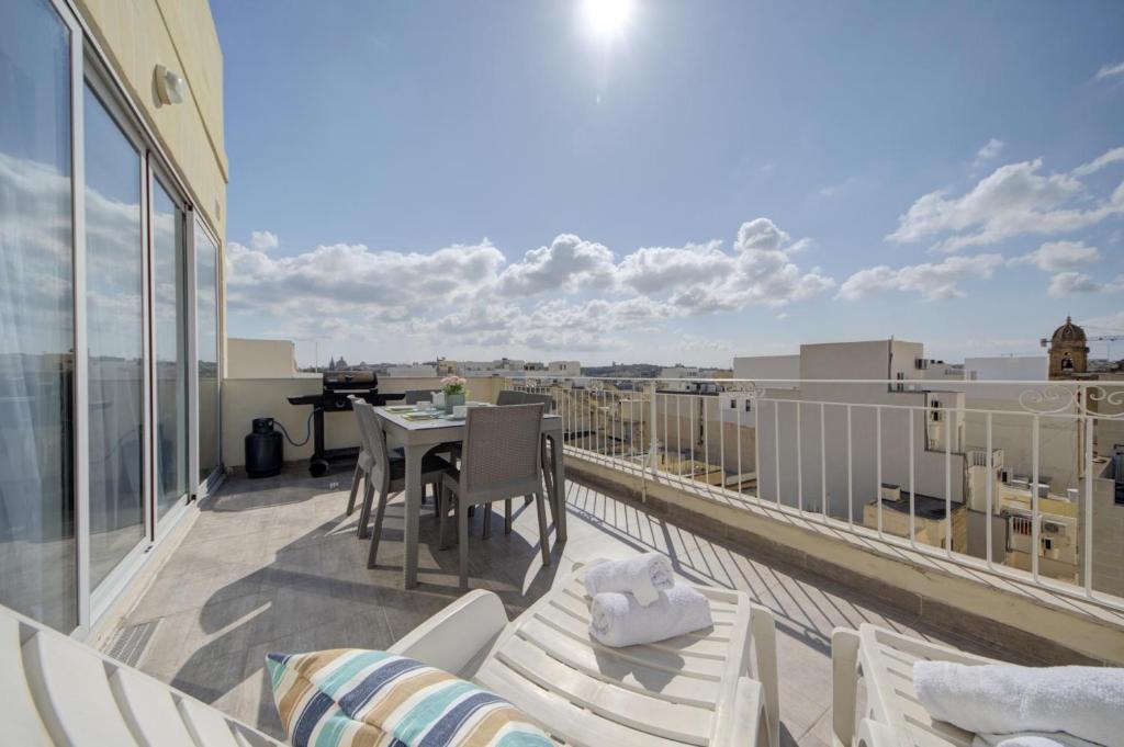 uma varanda com uma mesa e cadeiras num telhado em CityVista - Gzira Apartments and Penthouse by ShortletsMalta em Il-Gżira