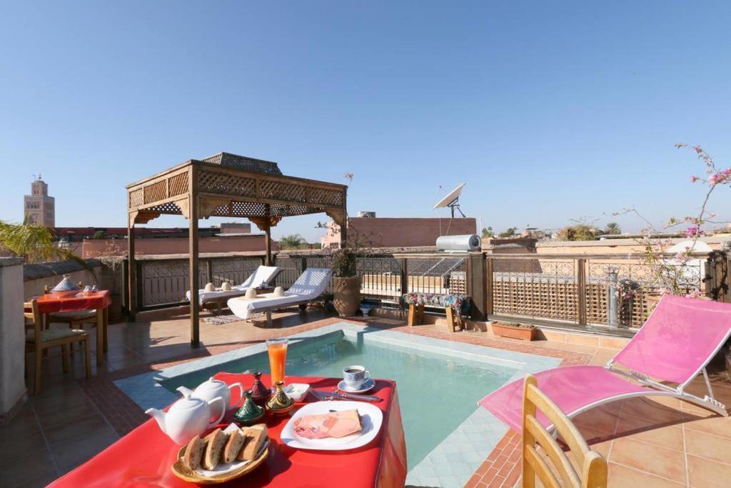 - une table avec une assiette de nourriture à côté de la piscine dans l'établissement Riad BB Marrakech, à Marrakech