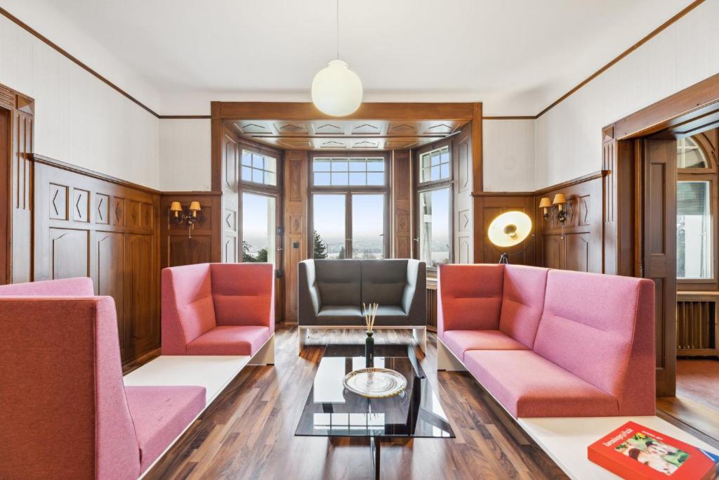 sala de estar con sillas rosas y mesa en Villa Bellevue Rüschlikon en Rüschlikon