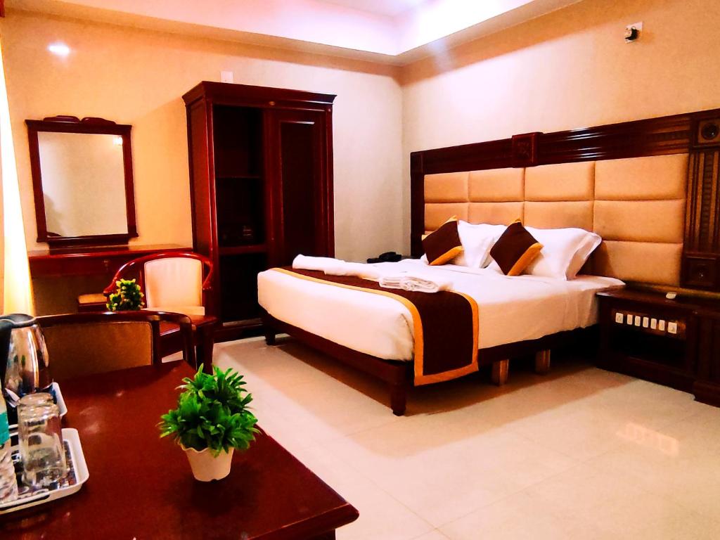 a bedroom with a large bed and a table at HOTEL YUVRAJ SIGNATURE in Mysore