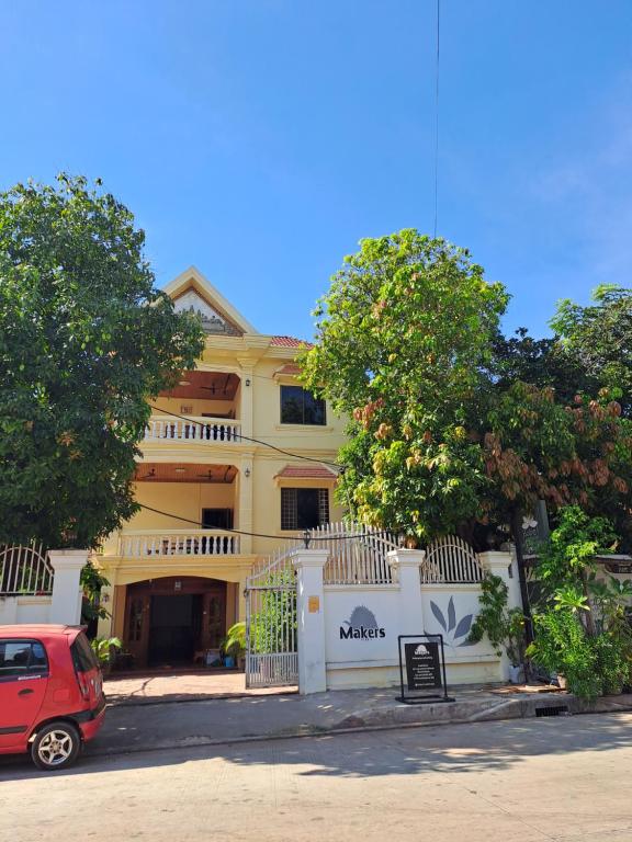 a red car parked in front of a yellow building at Makers Guesthouse in Siem Reap