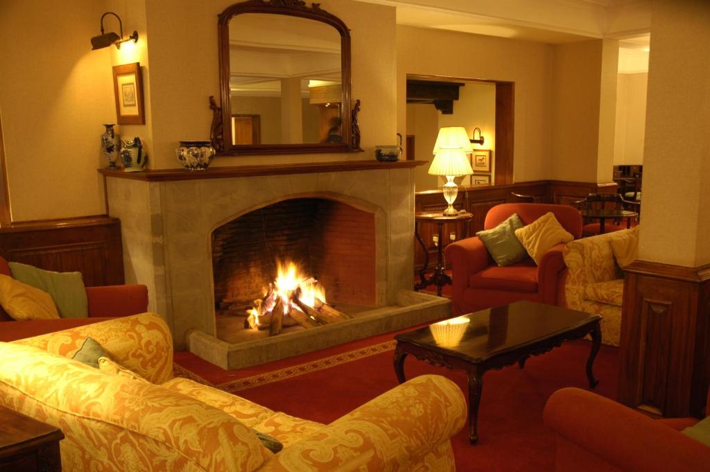 a living room with a fireplace with couches and a mirror at Arusha Serena Hotel in Nkoanrua
