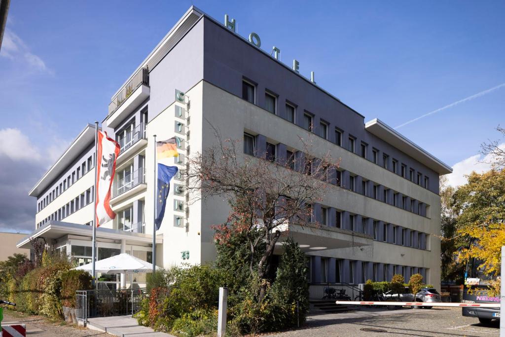 un edificio blanco con una bandera delante de él en Familienhotel Citylight en Berlín