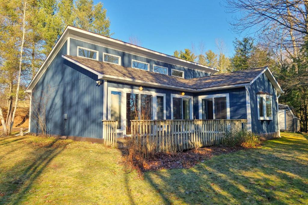 una casa azul en un campo con un patio en Riverbend Retreat, en Jay