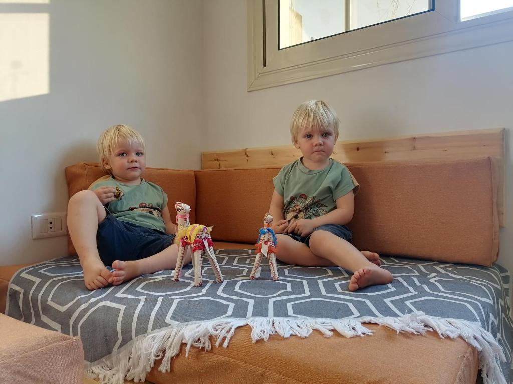 Dois rapazes sentados numa cama com bonecas de brincar. em Champollion Hostel no Cairo