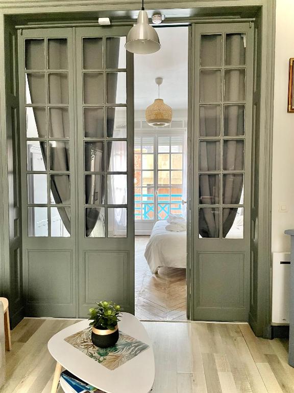 Cette chambre dispose de portes vertes, d'une table et d'un lit. dans l'établissement La Batelière, appartement mer avec patio privé, à Mers-les-Bains