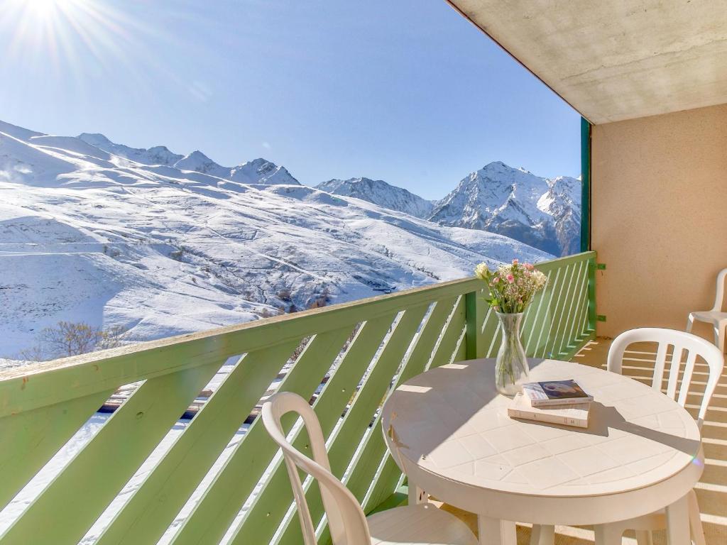 una mesa y sillas en un balcón con montañas cubiertas de nieve en Vacancéole - Les Balcons du Soleil, en Germ