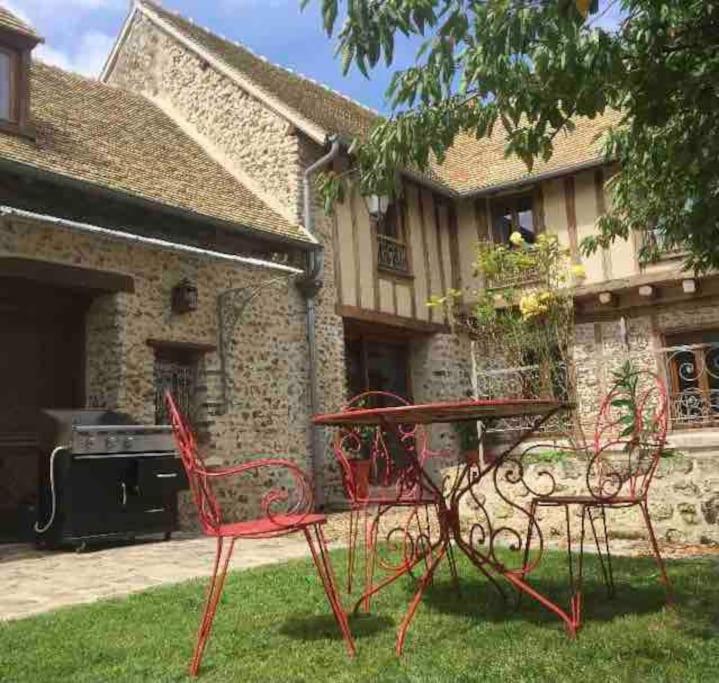 una mesa de picnic y sillas frente a una casa en Maison avec exterieur, en Bû