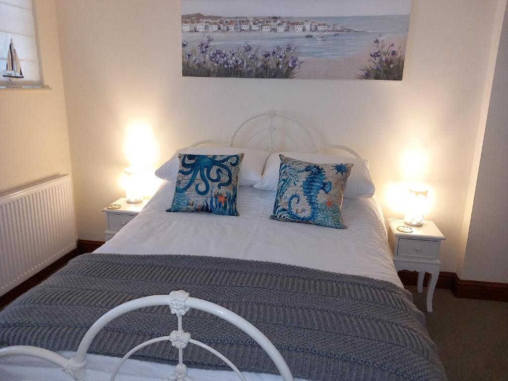 a bedroom with a white bed with blue pillows at Belv House in Weymouth