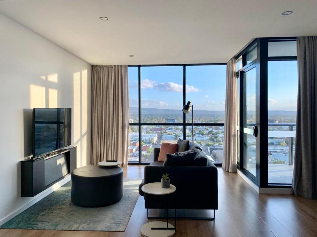 a living room with a couch and a large window at CBD Stunning TOP Floor View - FREE Parking FREE Netflix FREE Gym FREE Pool FREE Sauna FREE BBQ Area FREE Coffee in Adelaide