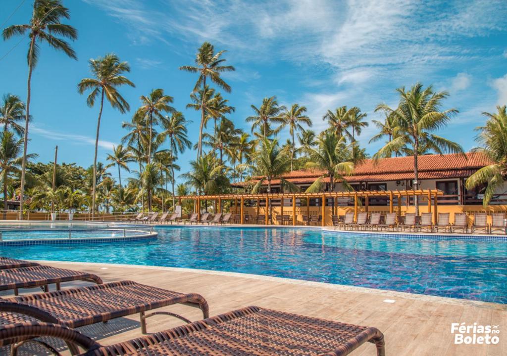 uma piscina de resort com palmeiras ao fundo em PSP Resort All Inclusive em Porto Seguro