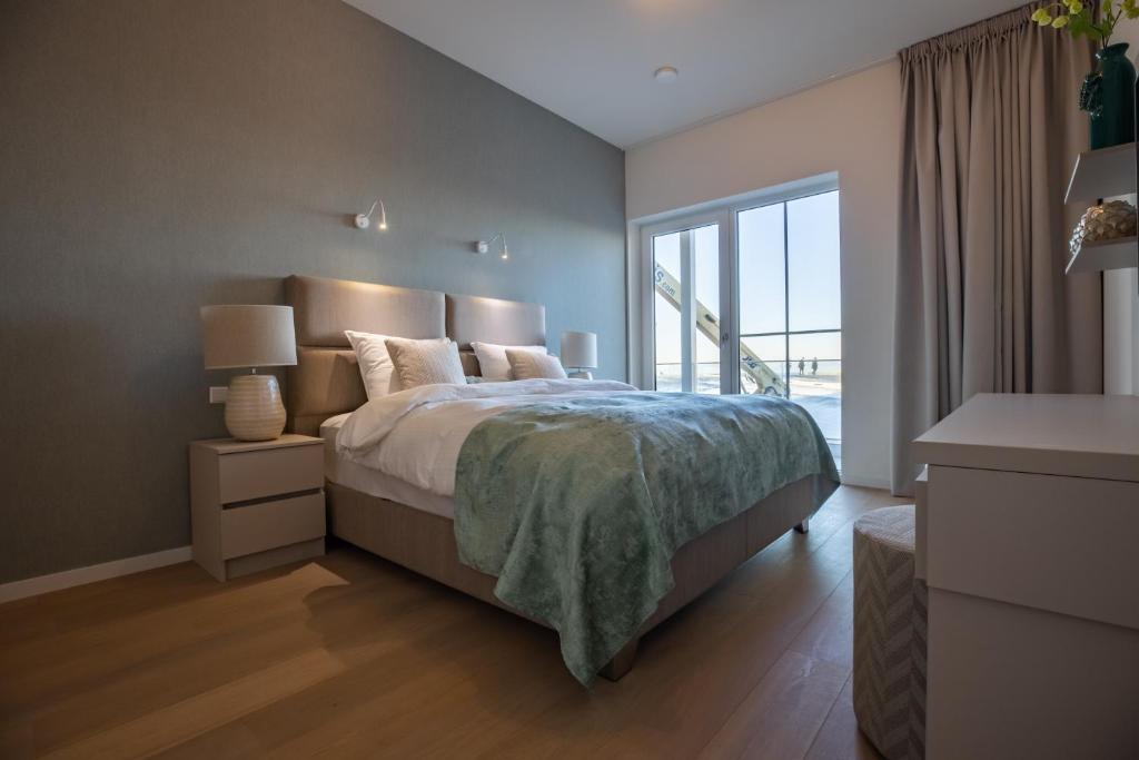 a bedroom with a bed and a large window at The Harbour luxurious, use of hotel swimming pool and sauna in Cadzand