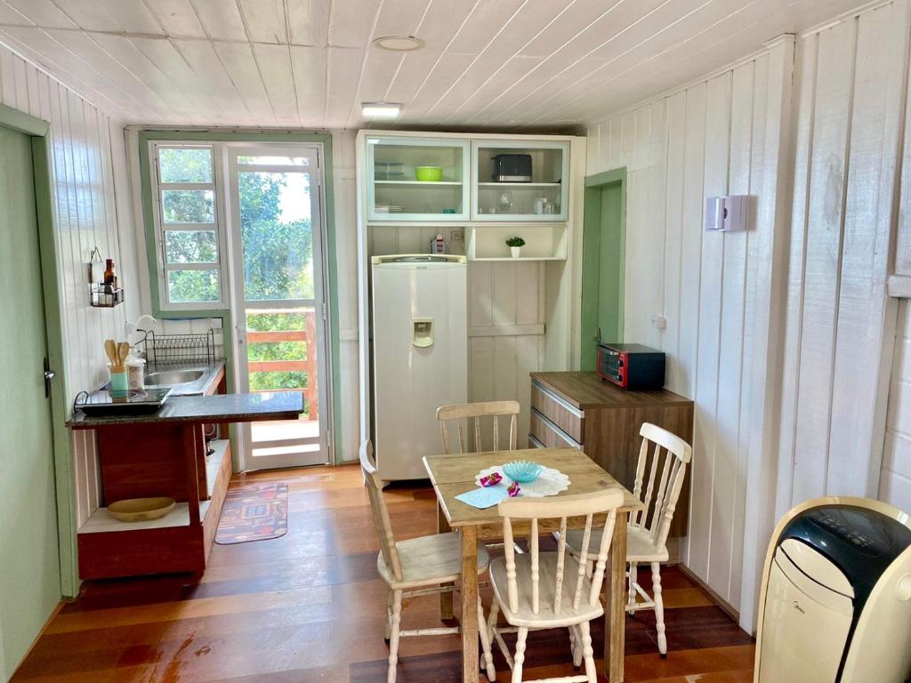 a kitchen with a table and chairs and a refrigerator at GREEN HOUSE - com linda vista para o mar in Palhoça