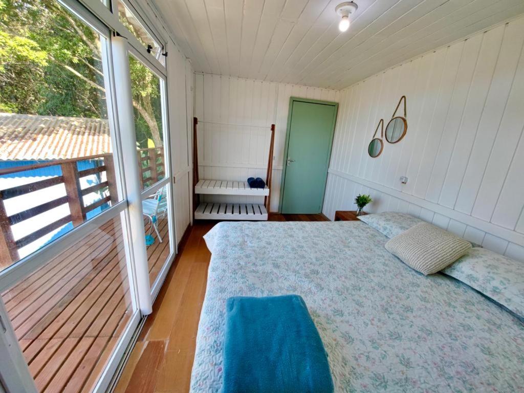 1 dormitorio con cama y ventana grande en GREEN HOUSE - com linda vista para o mar, en Palhoça