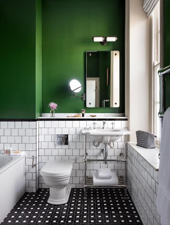 a green and white bathroom with a toilet and a sink at The Randolph Hotel Oxford, a Graduate by Hilton Hotel in Oxford