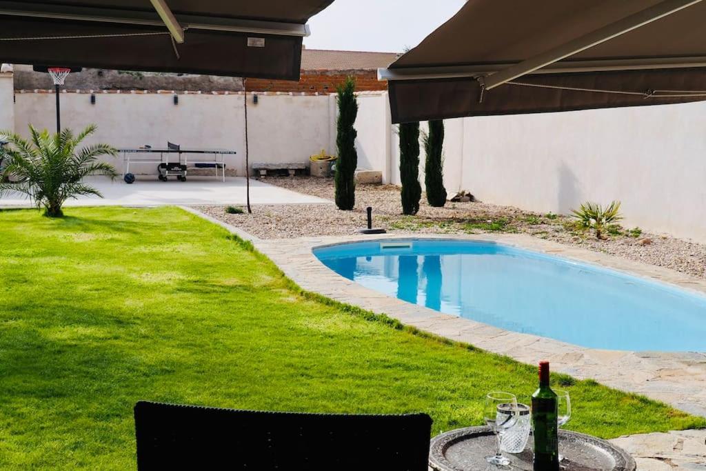 um quintal com uma piscina e uma mesa com uma garrafa de vinho em Villa Mandrés. Casa con jardín y piscina. Proximo a Puy Du Fou. em Totanés