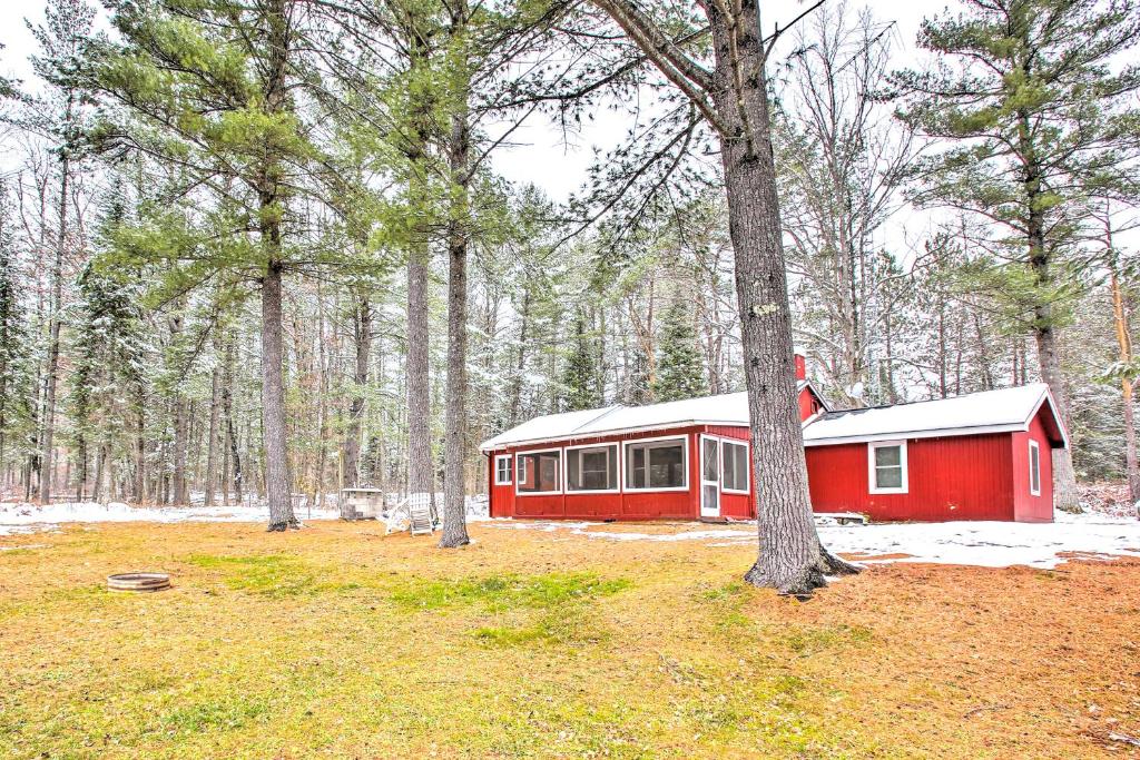 una cabaña roja en medio de un bosque en Peaceful Traverse City Cabin about 16 Mi to Dtwn!, en Traverse City