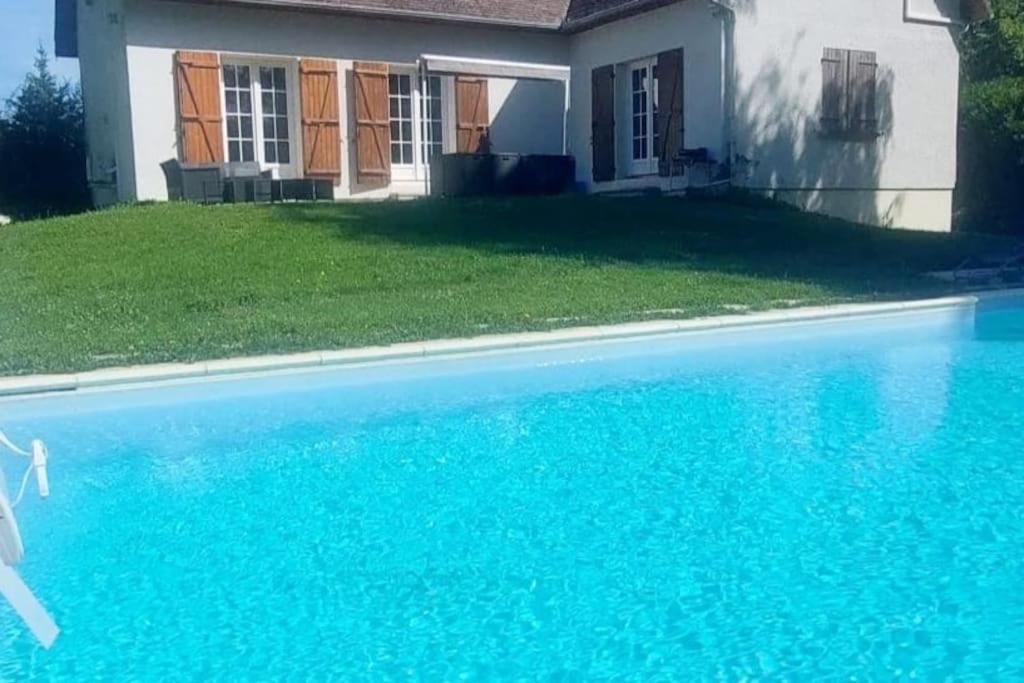 a blue swimming pool in front of a house at La villa du lac à Mesnil Saint Père in Mesnil-Saint-Père