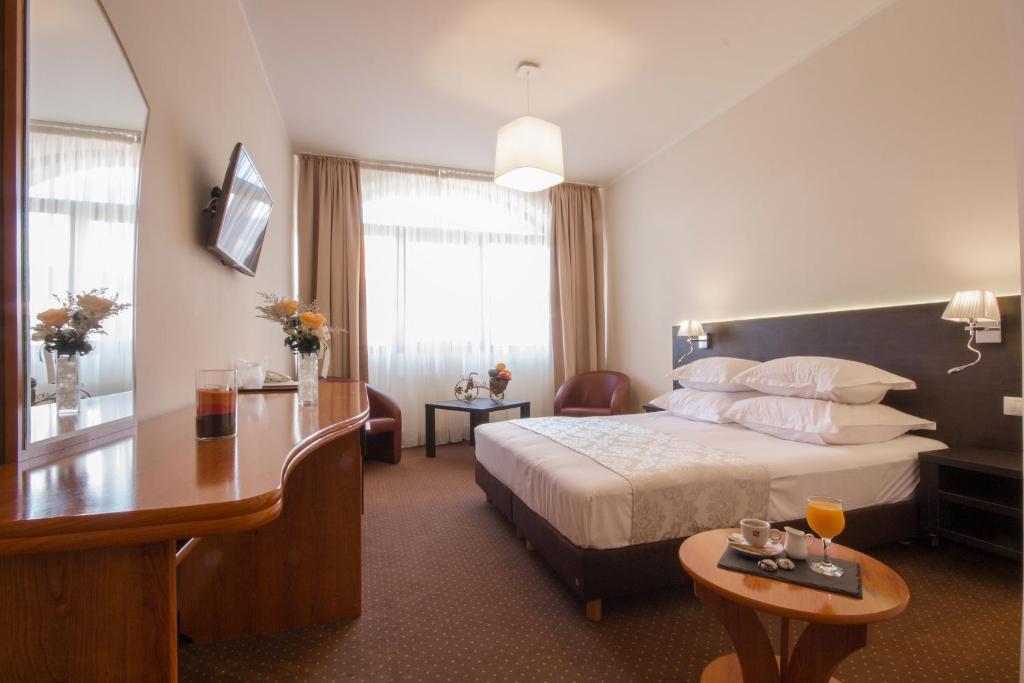 ein Hotelzimmer mit einem großen Bett und einem Tisch in der Unterkunft Restaurant Pensiune Bucovina in Câmpulung Moldovenesc