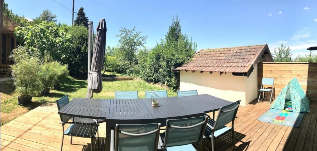 a table with chairs and an umbrella on a deck at La Maison du Bonheur in Lons-le-Saunier