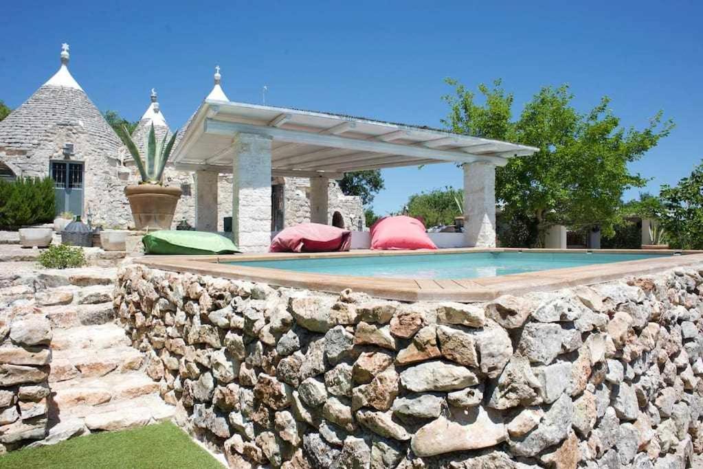 una pared de piedra junto a la piscina en Tenuta Bianca with amazing exclusive pool, en Ostuni