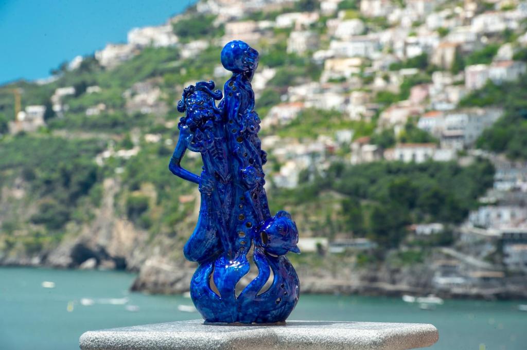 a blue glass statue of a woman and a cat at La Perla di Nettuno in Furore
