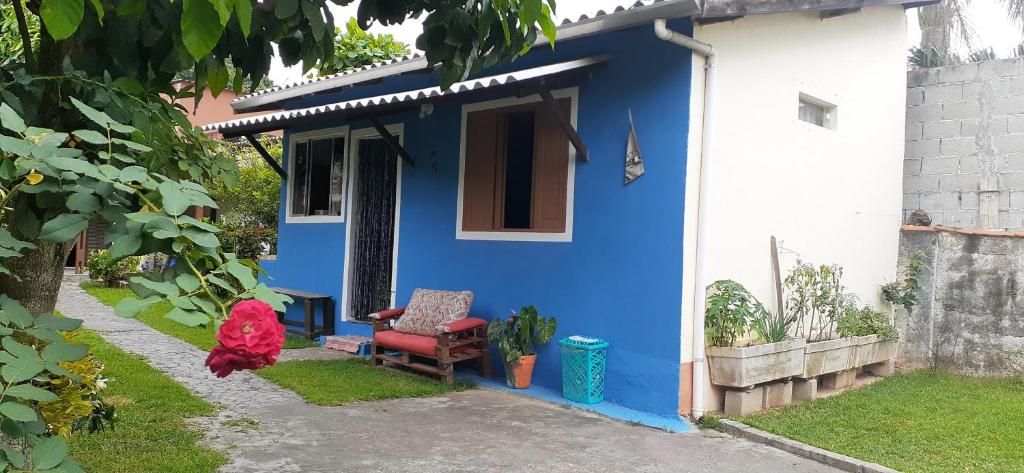 uma casa azul e branca com uma cadeira num quintal em Casinha de hóspedes aconchegante. em São Sebastião