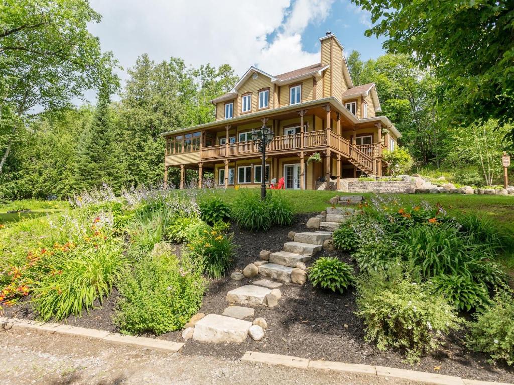 a wooden house with a garden in front of it at Les Dames du Lac in Mont-Tremblant