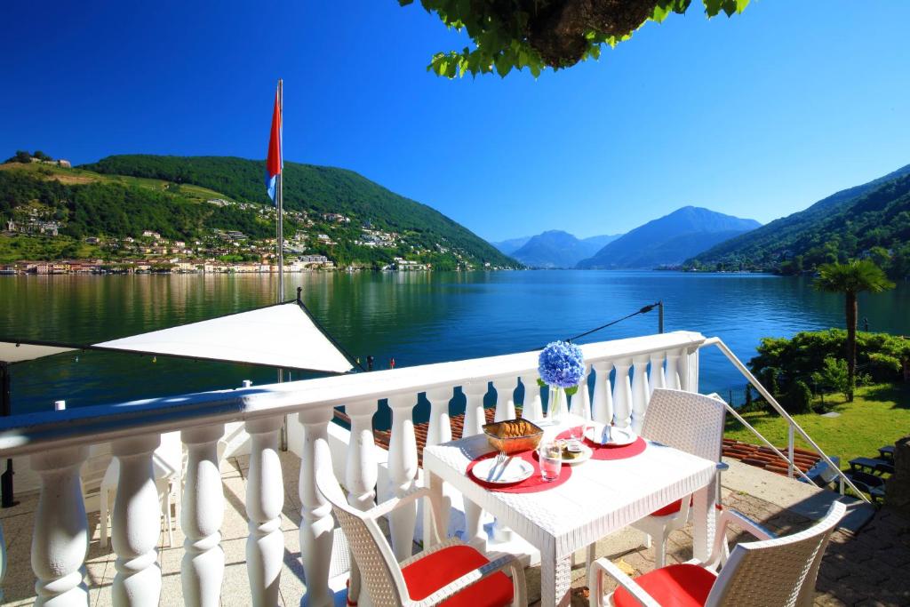 a balcony with a table and chairs and a view of a lake at Zappa Lake Lodge in Brusino Arsizio