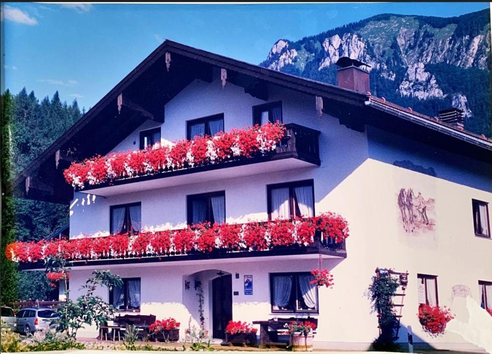 ein Gebäude mit roten Blumen auf der Seite in der Unterkunft Feichten-Hof Zaiser Zimmer in Schleching