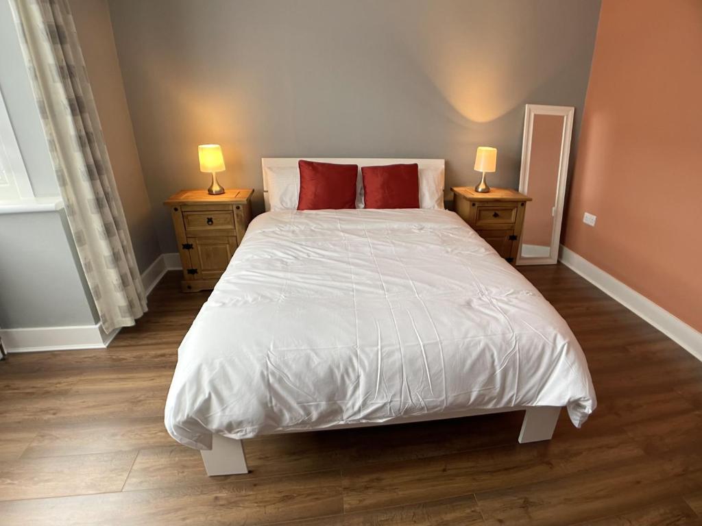 a bedroom with a white bed with red pillows at Richmond HOUSE in Slough