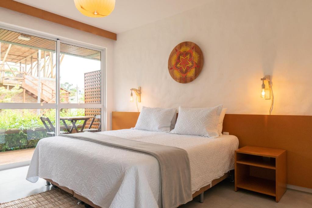 een slaapkamer met een bed en een groot raam bij Pousada Rosa Tropicalia in Praia do Rosa
