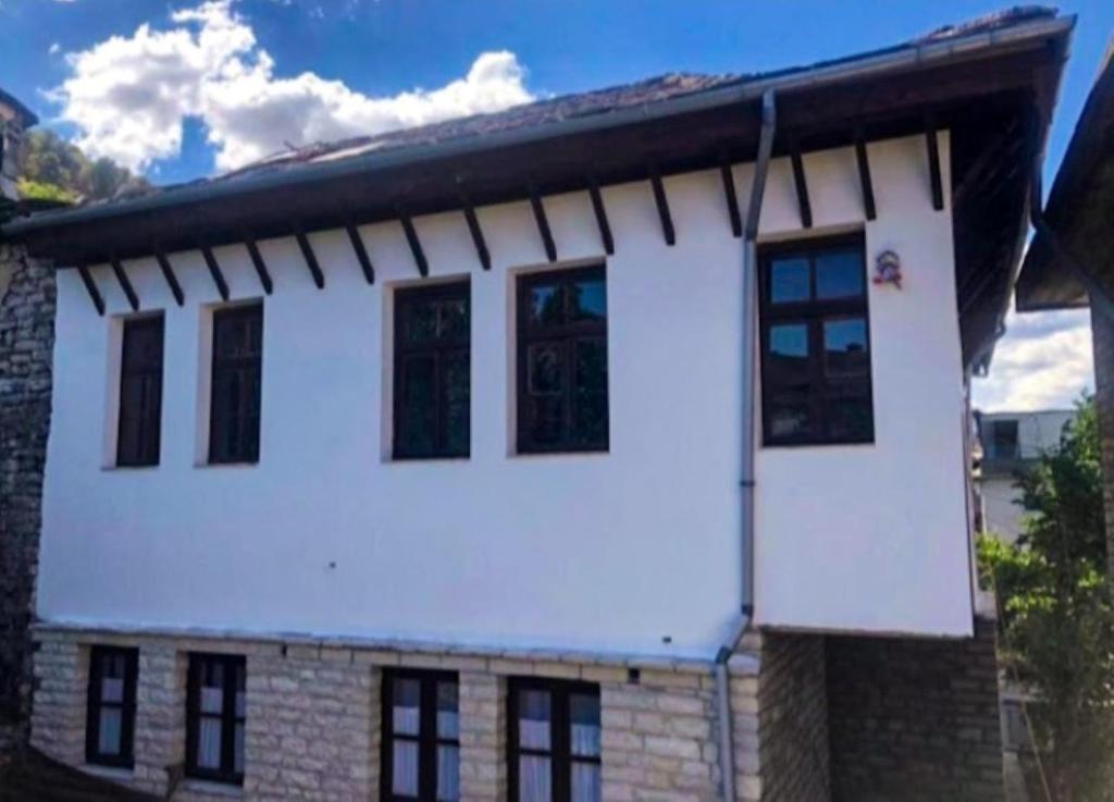 una casa con puertas blancas y ventanas negras en MiziriGuestHouse, en Gjirokastra