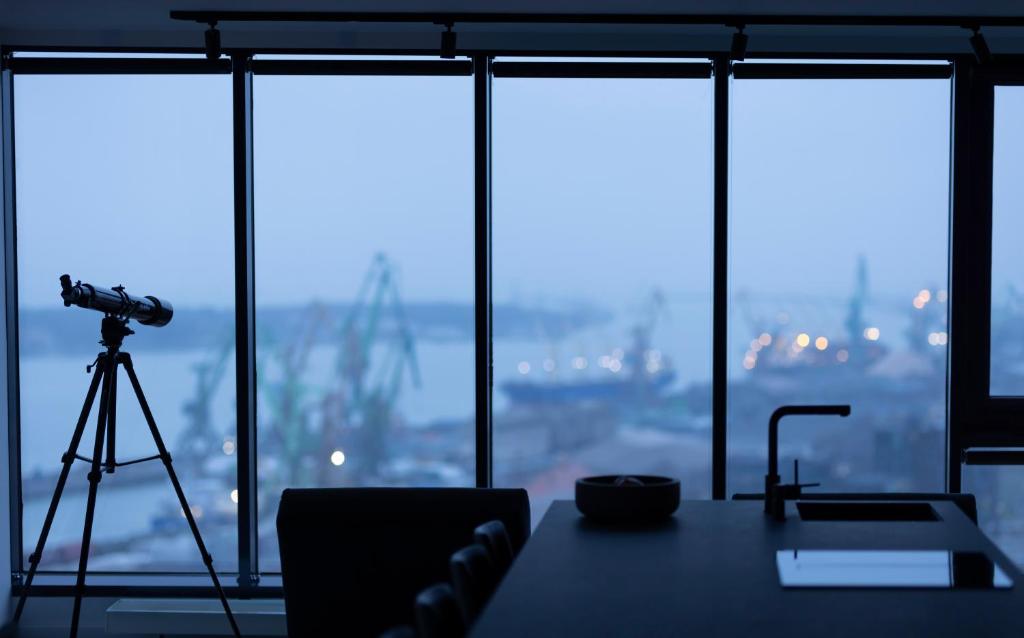 a camera on a tripod next to a room with windows at Sky Garden Penthouse in Klaipėda