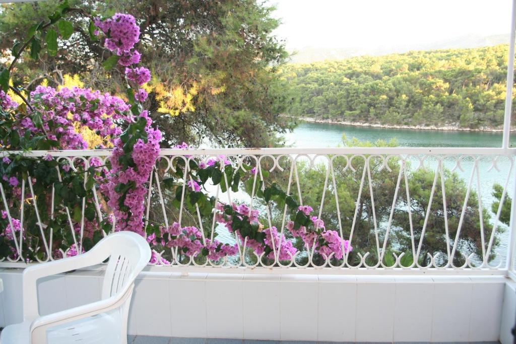 a white chair sitting on a balcony with purple flowers at Apartment Bugenvila in Vrboska