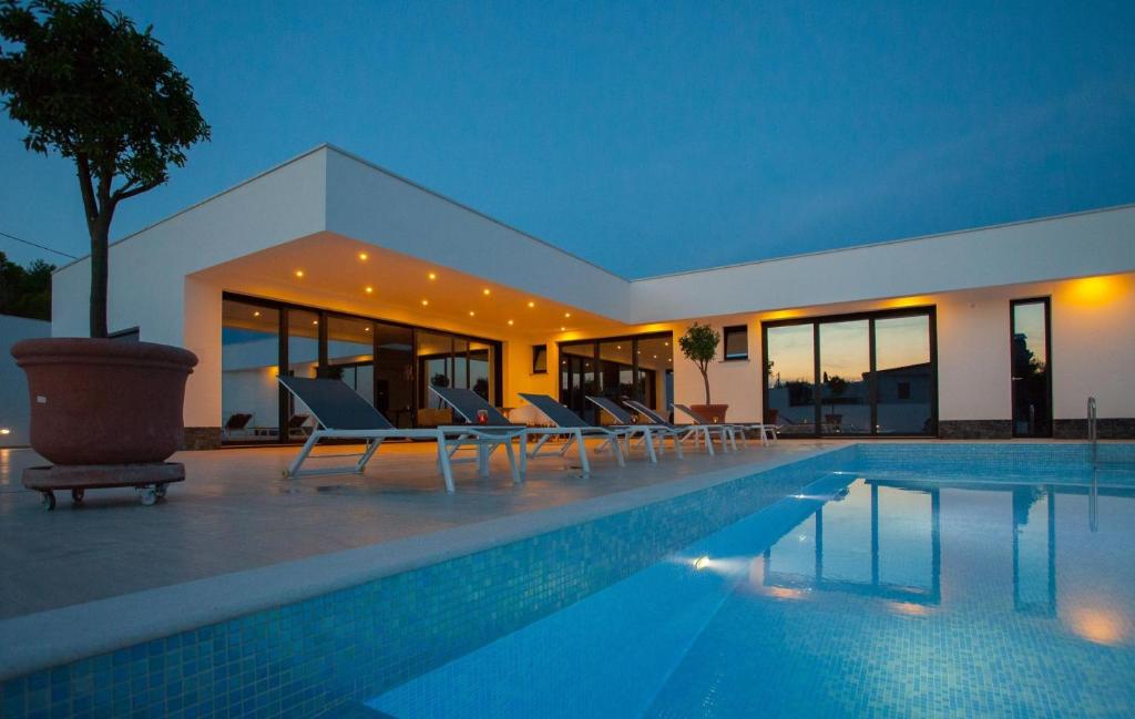 une villa avec une piscine la nuit dans l'établissement Villa Garma Beachfront - 3 Bedroom villa - Stunning Sea Views - Gym - Private Pier, à Potirna