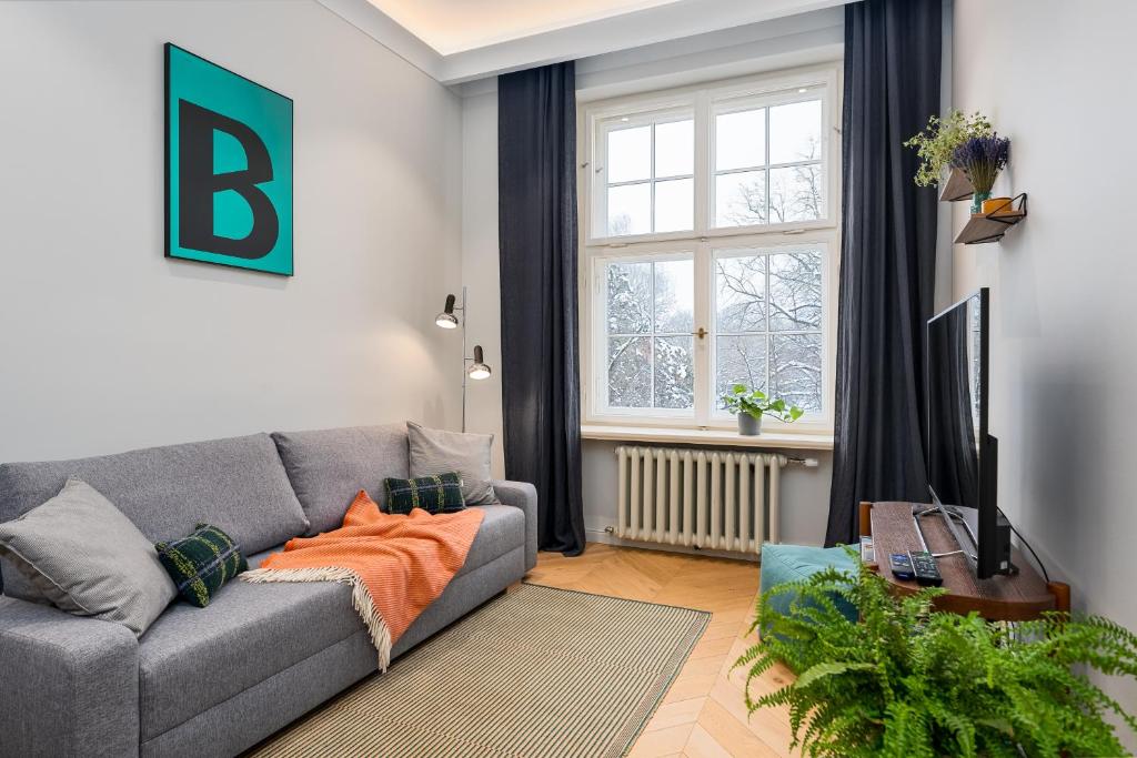 uma sala de estar com um sofá cinzento e uma janela em Smart park view studio in heart of Riga 5 min to Old Town em Riga