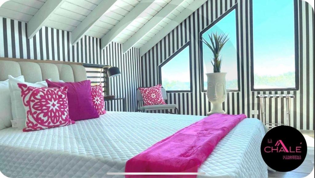 La Chalé Parguera في لاخاس: غرفة نوم بسرير كبير مع وسائد وردية وبيضاء