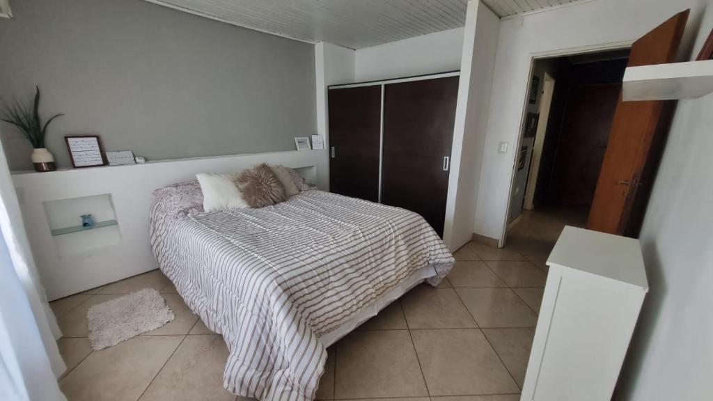 Dormitorio blanco con cama y armario en Hospedaje "LUZ" en Olavarría