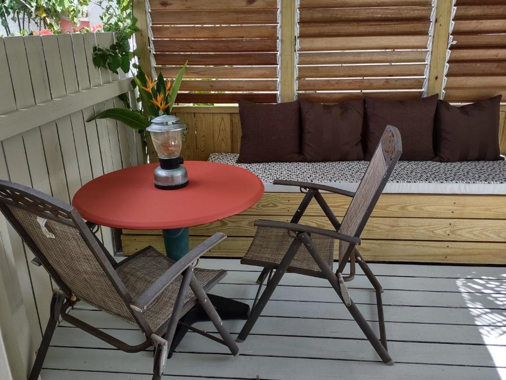 a table and two chairs on a porch with a bench at Private Garden Suite, Surf, Work, Relax in Christ Church