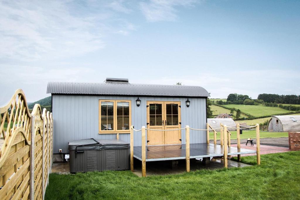 a tiny house with a deck and a fence at Lily in Rhayader