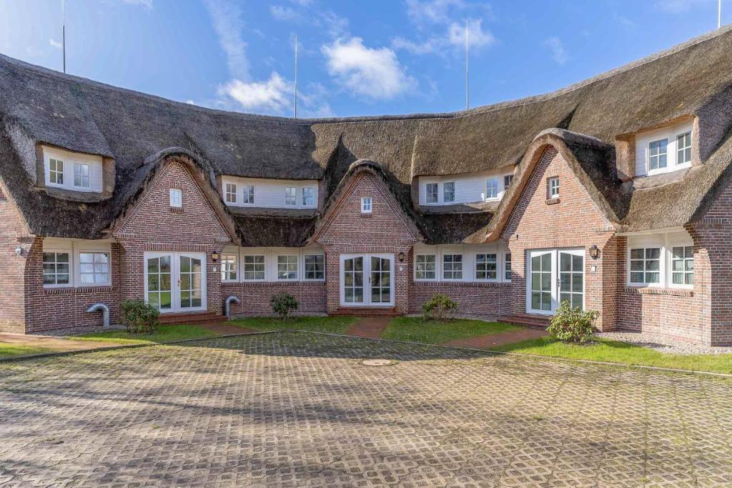 een groot bakstenen huis met een rieten dak bij Lieblingsplatz in Sankt Peter-Ording